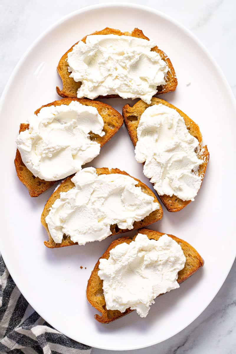 Large white platter with toast topped with creamy ricotta cheese