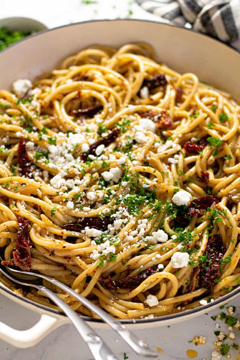 Close up shot of a large white pan filled vegan sun dried tomato pasta