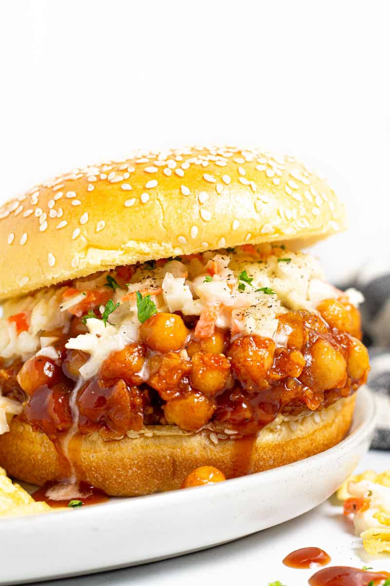 Close up shot of a BBQ chickpea sandwich dripping with barbecue sauce
