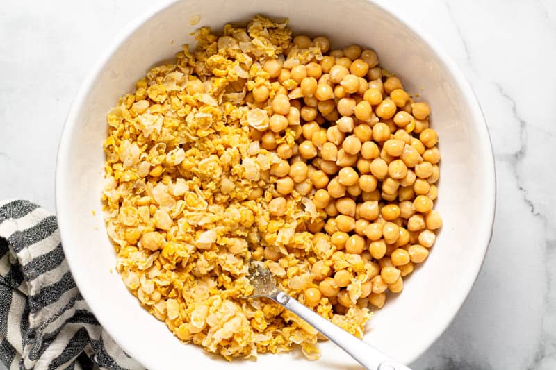 Large white bowl filled with chickpeas half of which are mashed
