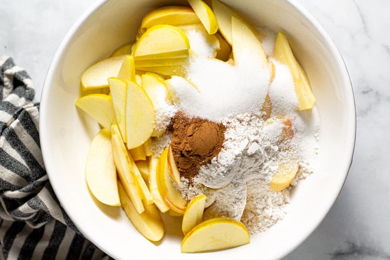 Large white bowl filled with ingredients to make apple crisp filling