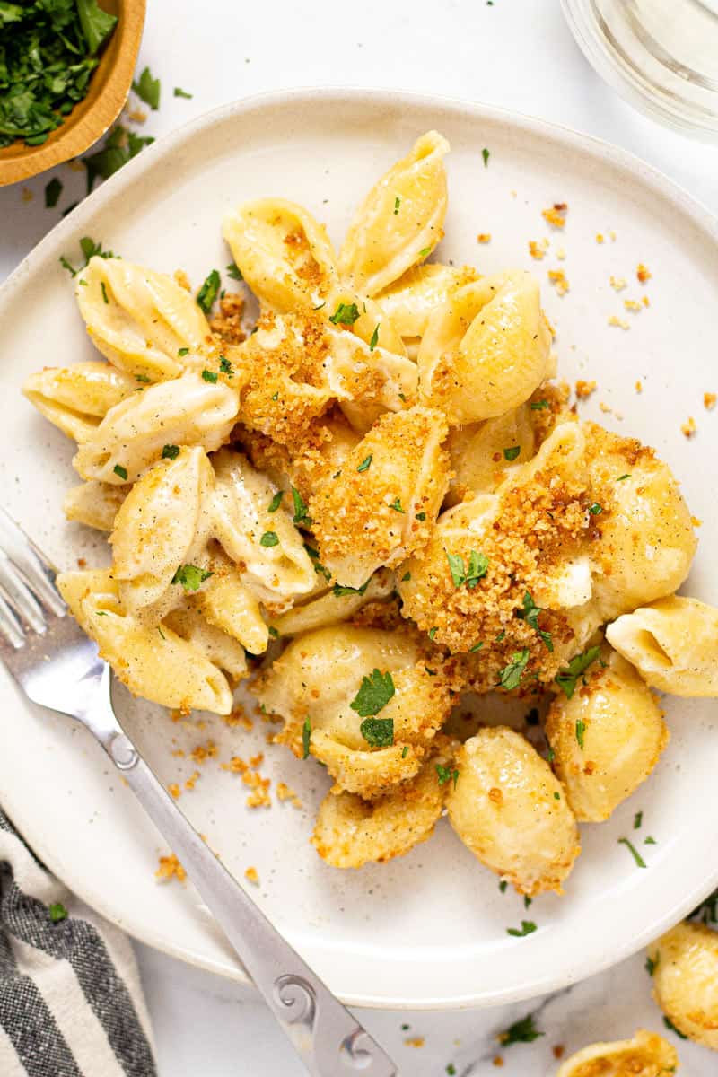 Close up shot of a white plate with Brie mac and cheese topped with cracker crumb topping