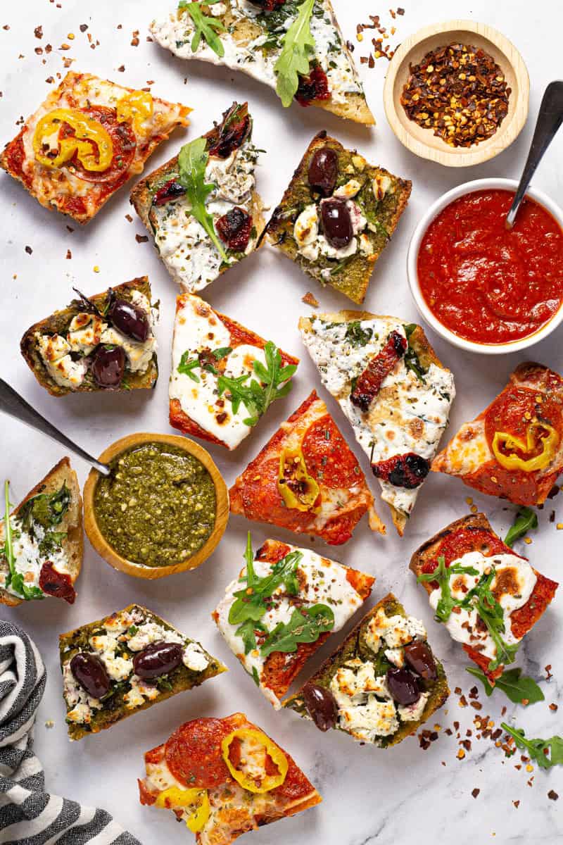 White marble counter top with slices of French bread pizza garnished with red pepper flakes
