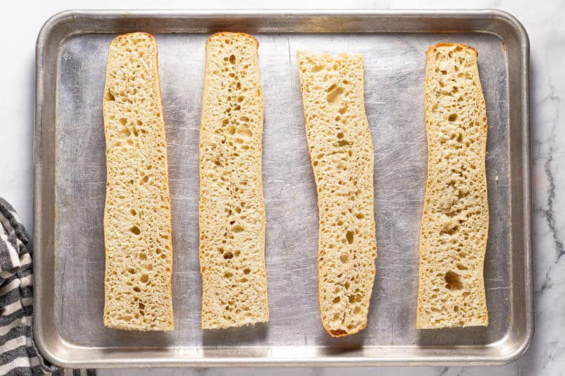 Baking sheet with sliced French bread on it