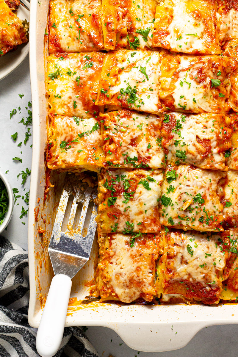Large white baking dish filled with homemade Mediterranean lasagna garnished with fresh parsley 