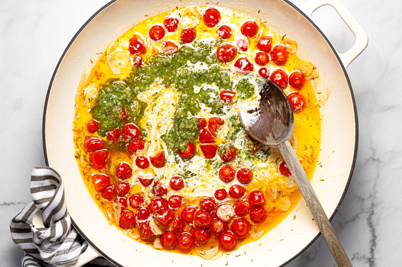 Large white pan with ingredients for creamy pesto sauce with tomatoes 