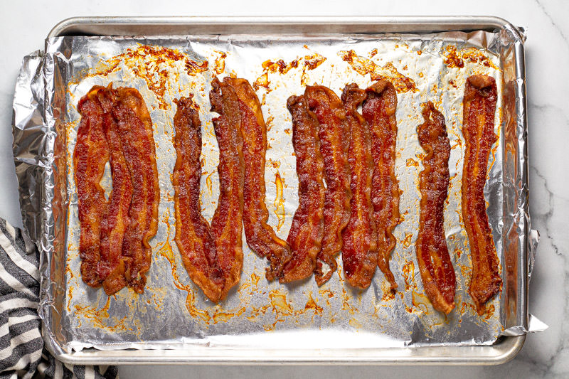 Baked bacon on a tin foil lined baking sheet 