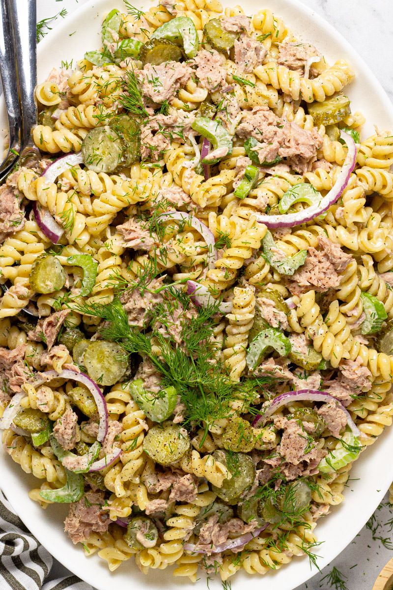 Large white platter filled with homemade tuna pasta salad garnished with fresh dill 