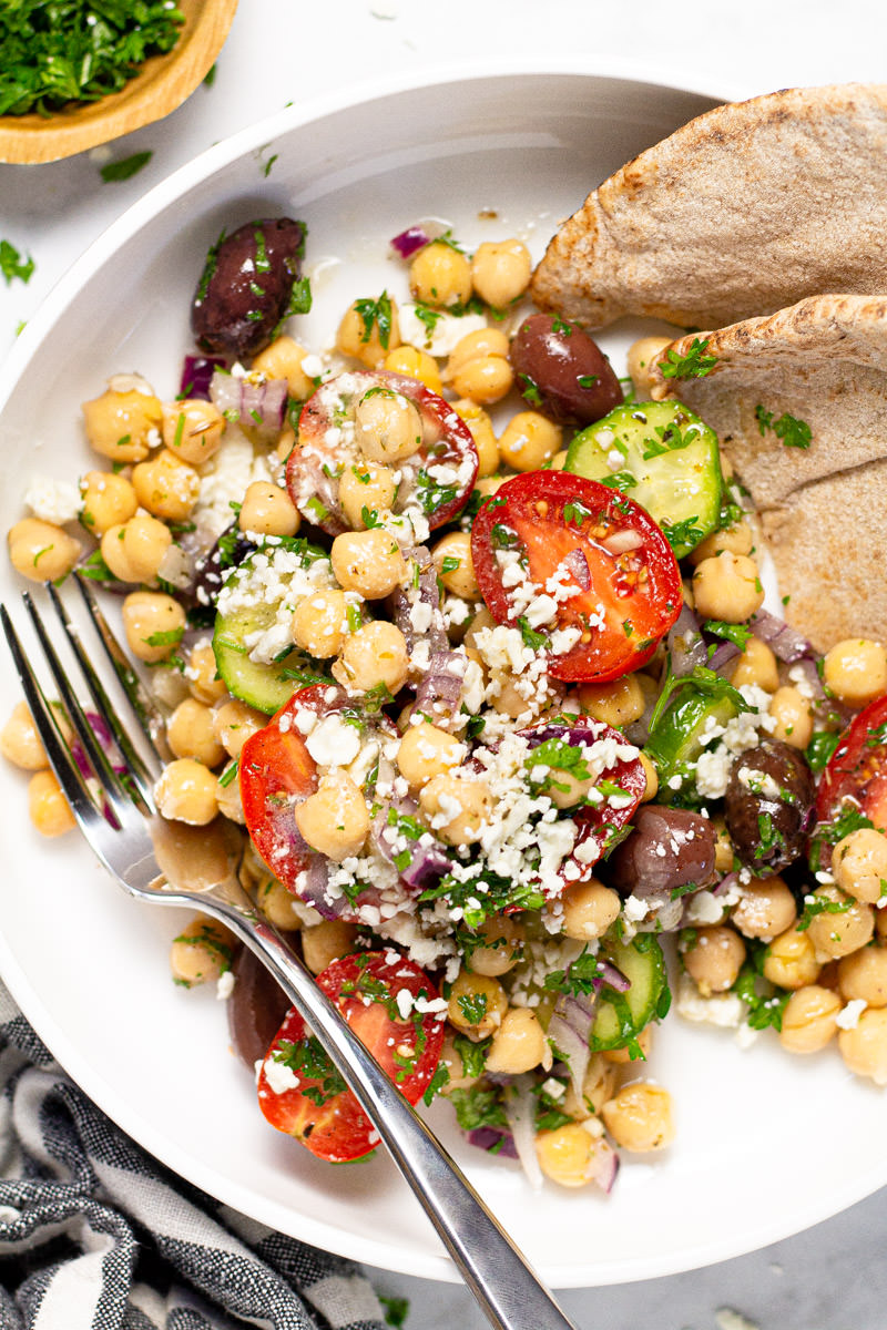 Large white bowl with Greek chickpea salad garnished with fresh parsley 