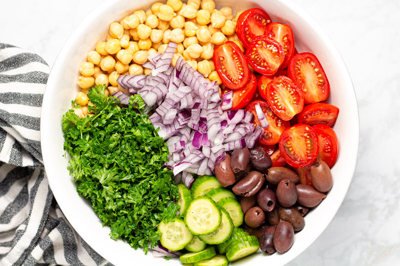 White bowl filled with ingredients to make a Mediterranean chickpea salad