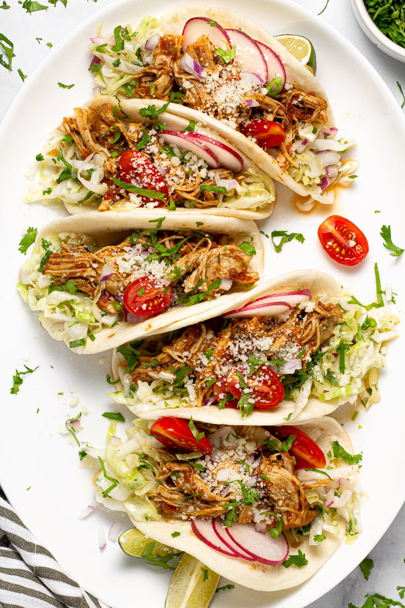Large white platter with 5 chicken tacos loaded with cilantro slaw