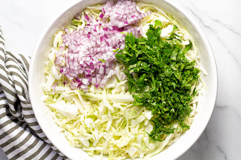 White bowl filled with ingredients to make homemade cilantro lime slaw