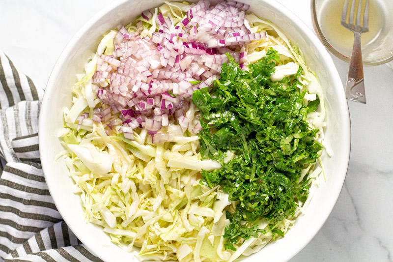 White bowl filled with ingredients to make homemade cilantro lime slaw