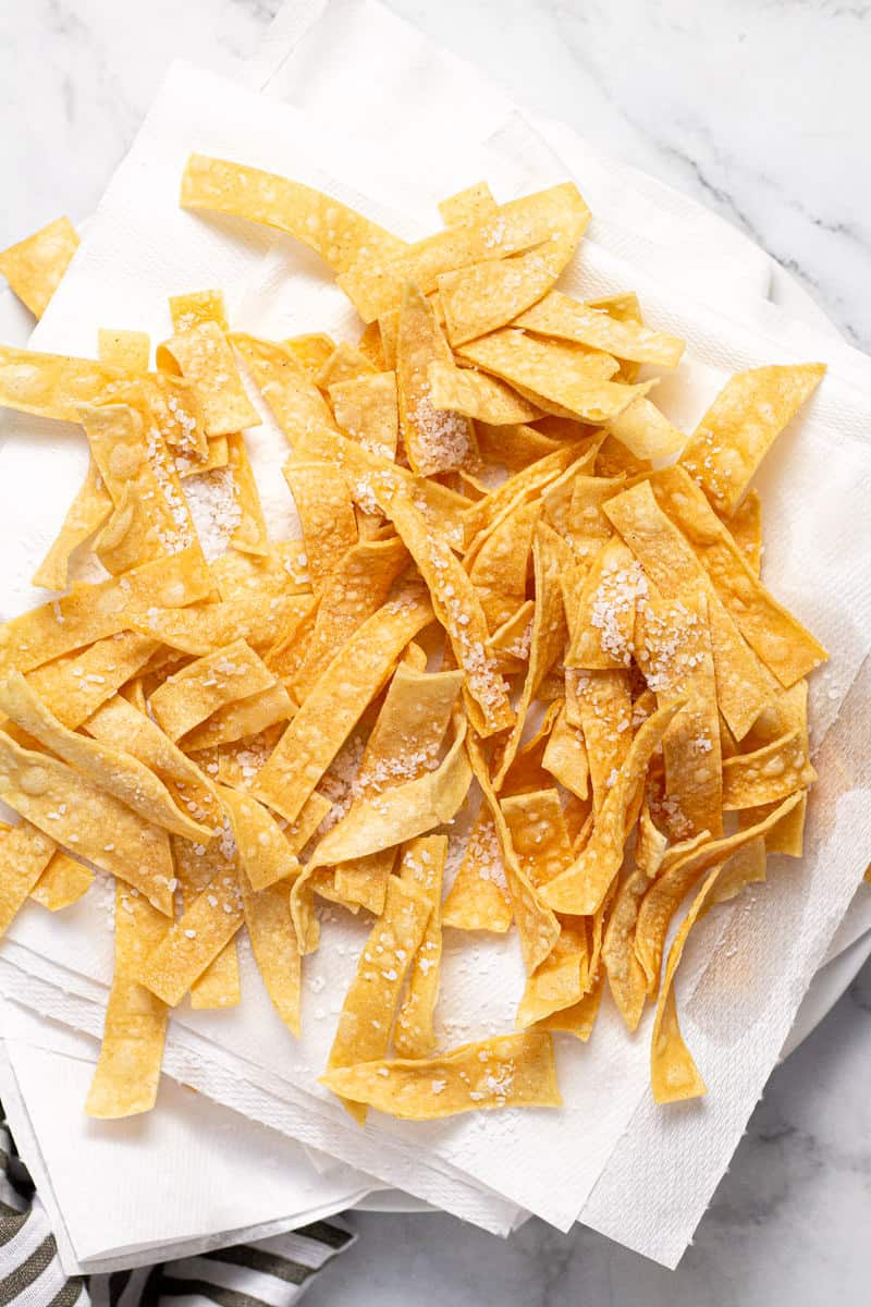 White paper towel lined plate with homemade fried tortilla strips on it