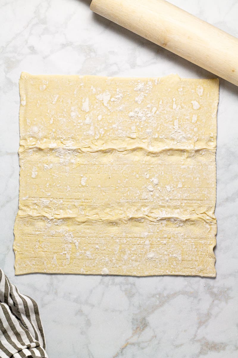 Gray marble counter top with puff pastry dough being rolled out