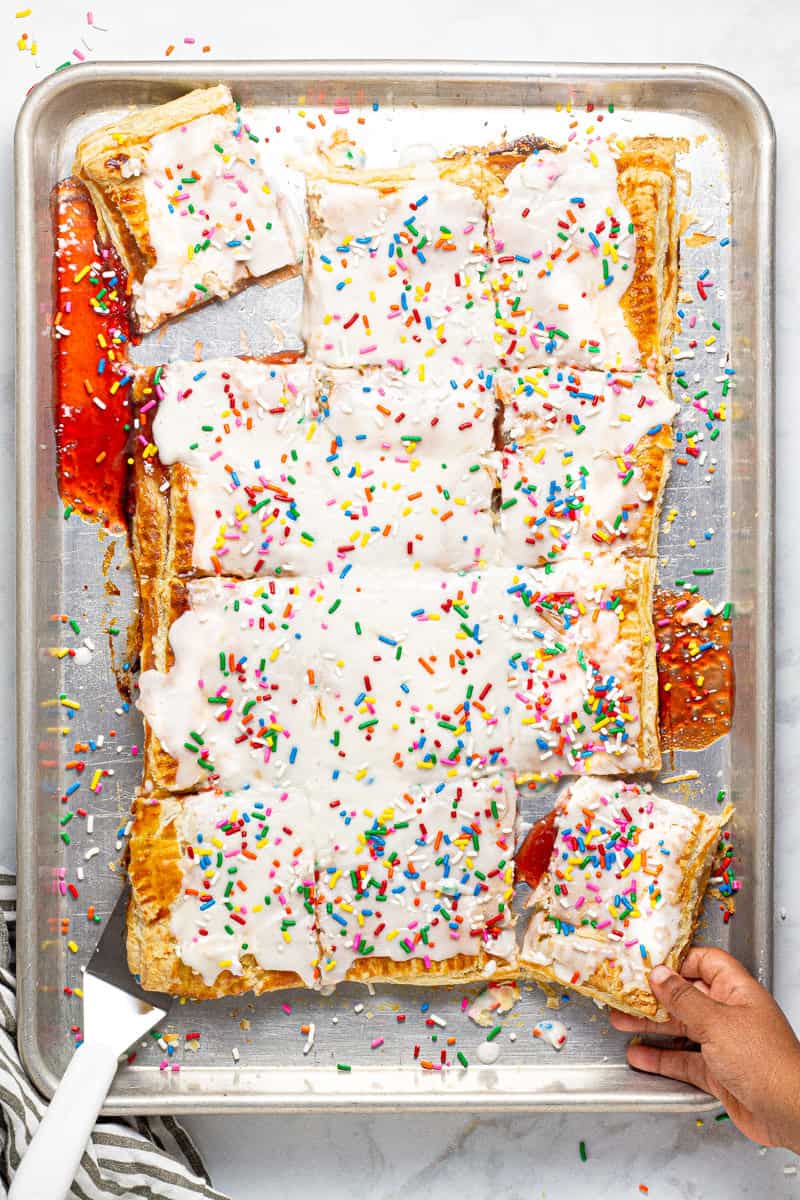 Giant strawberry pop tart on a large sheet pan with rainbow sprinkles