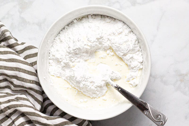 White bowl with powdered sugar and heavy cream in it