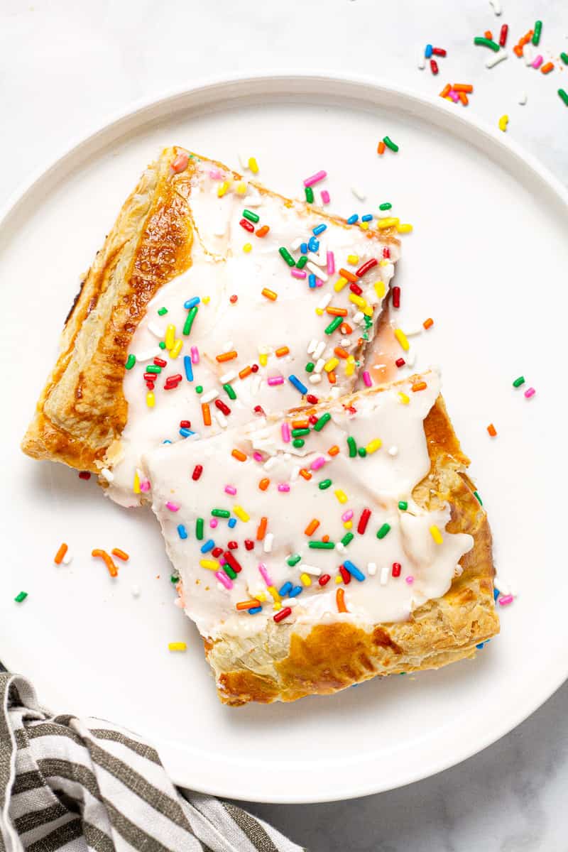 White plate with two homemade strawberry pop tarts garnished with rainbow sprinkles