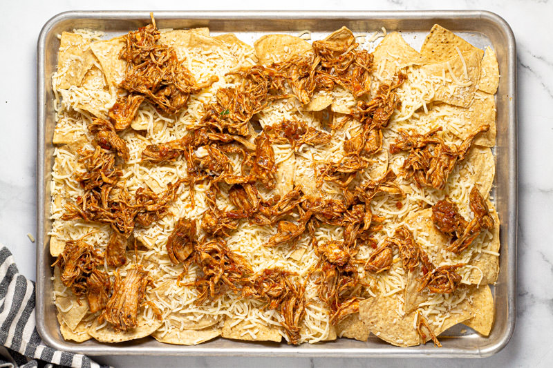 Baking sheet pan with tortilla chips shredded cheese and chicken