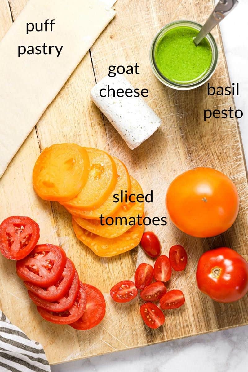 Overhead shot of a cutting board with ingredients to make a tomato tart