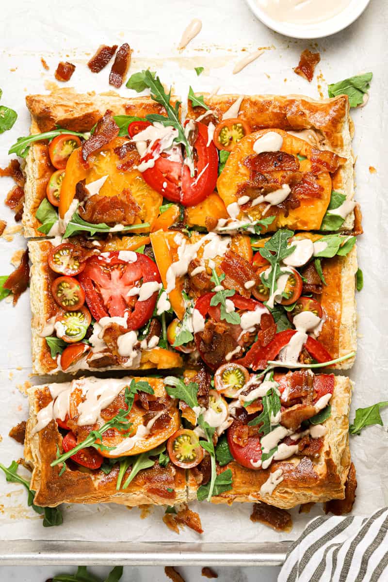 Overhead shot of a puff pastry BLT tart garnished with fresh arugula