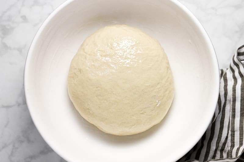 Beer pizza dough in a large white bowl with oil 