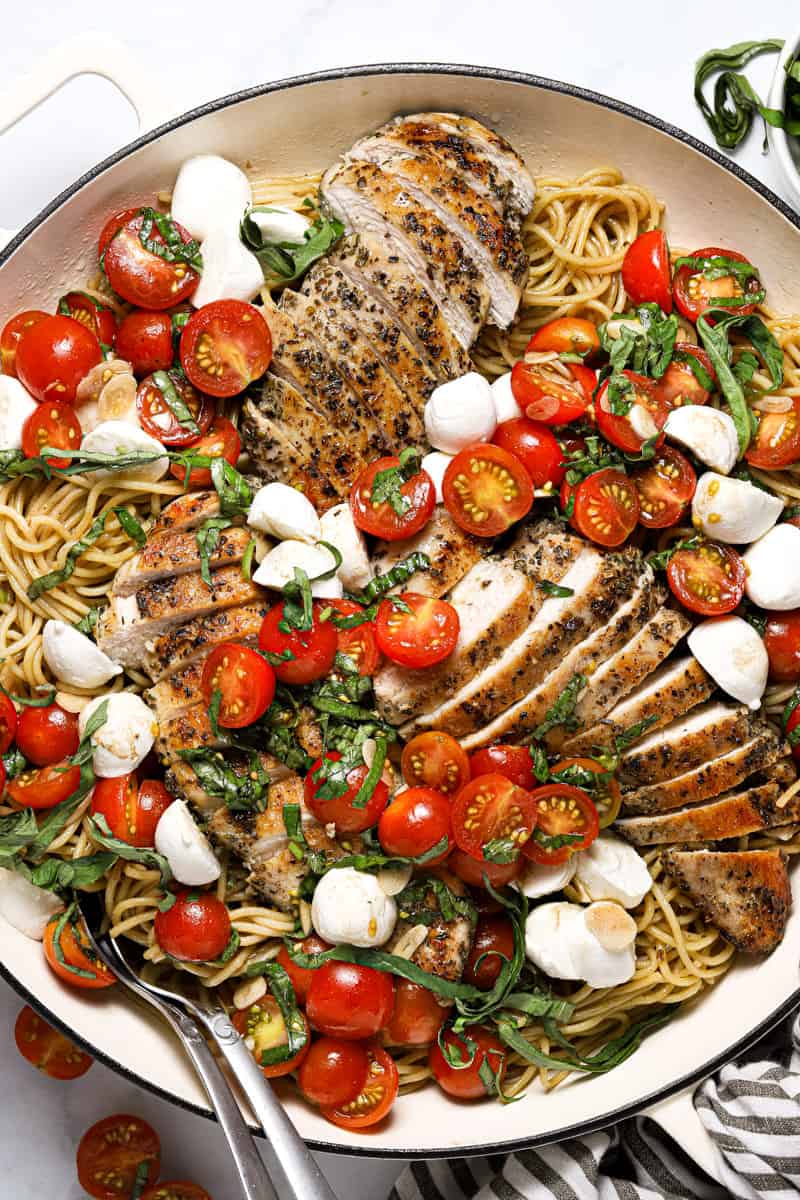 Overhead shot of a large white pan filled with spaghetti and bruschetta chicken