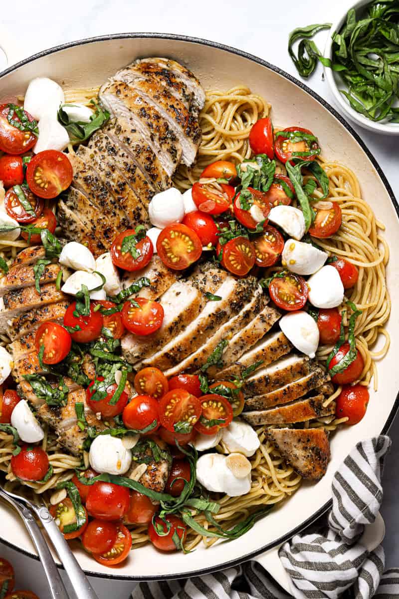 Overhead shot of a large white pan filled with spaghetti and bruschetta chicken