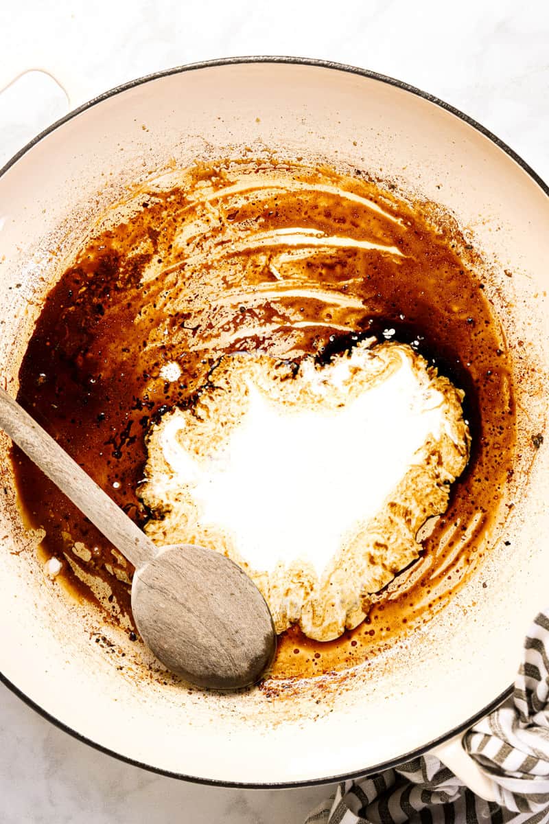 Large white pan with balsamic vinegar and heavy cream in it