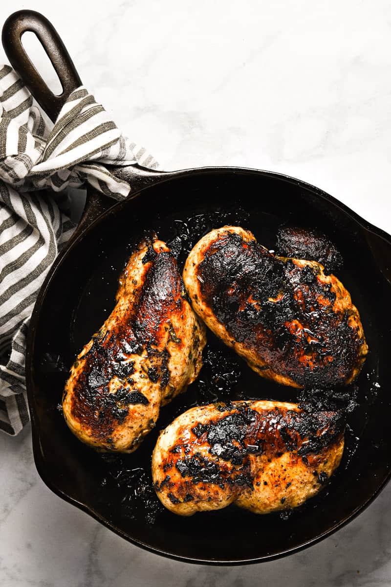 Overhead shot of a cast iron pan with golden brown sauteed chicken breast