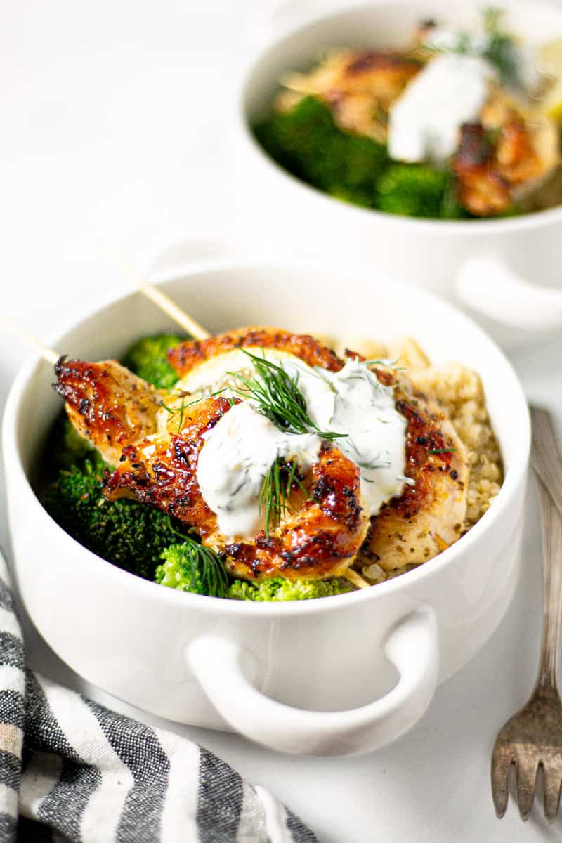 White bowl filled with Greek chicken kebabs quinoa and broccoli