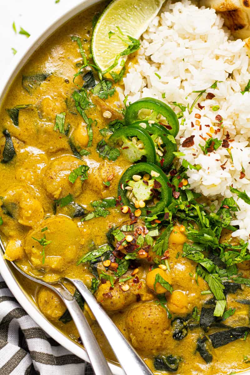 Close up of a bowl filled with rice and vegan curry garnished with fresh chopped cilantro