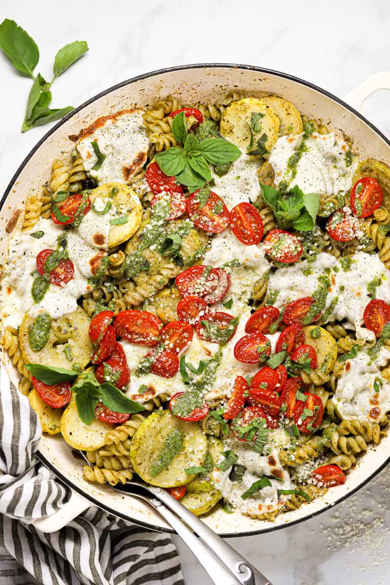 Overhead shot of a large pan of pesto pasta with tomatoes and mozzarella