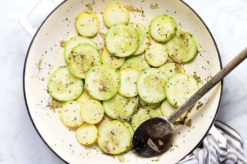 Large white pan with sliced zucchini squash and dried herbs