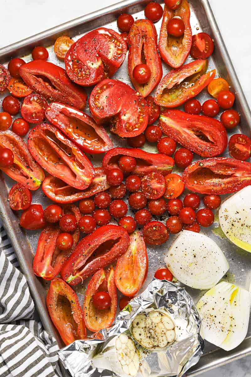 Sliced veggies on a baking sheet drizzled with olive oil and sprinkled with salt and pepper