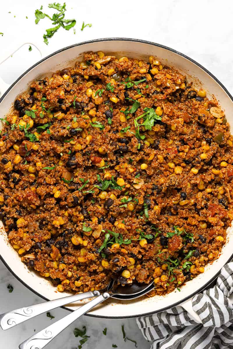 Mexican quinoa in a large white pan garnished with fresh chopped cilantro