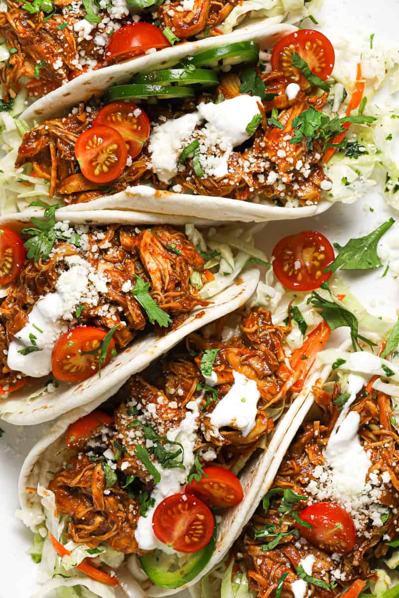 White platter filled with shredded BBQ chicken tacos garnished with fresh cilantro