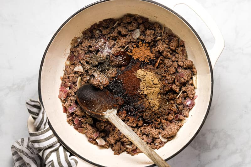 Large white pot filled with cooked ground beef and spices