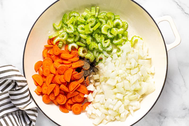 Carrots celery and diced onion in a large white skillet