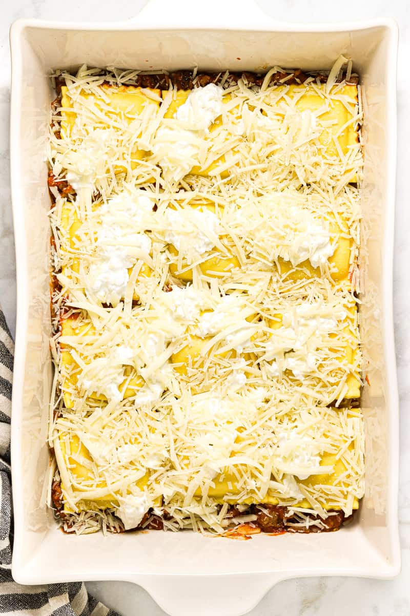 Large white pan filled with ingredients to make ravioli lasagna