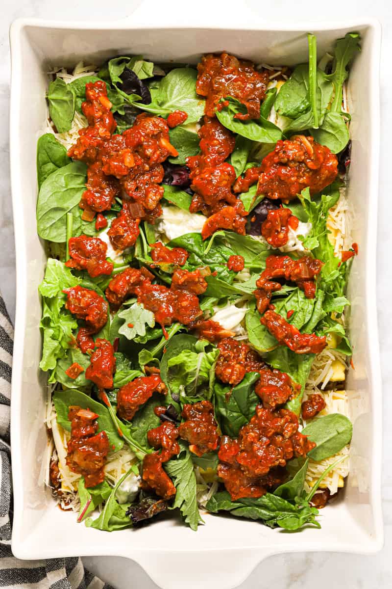 Large white pan filled with ingredients to make ravioli lasagna