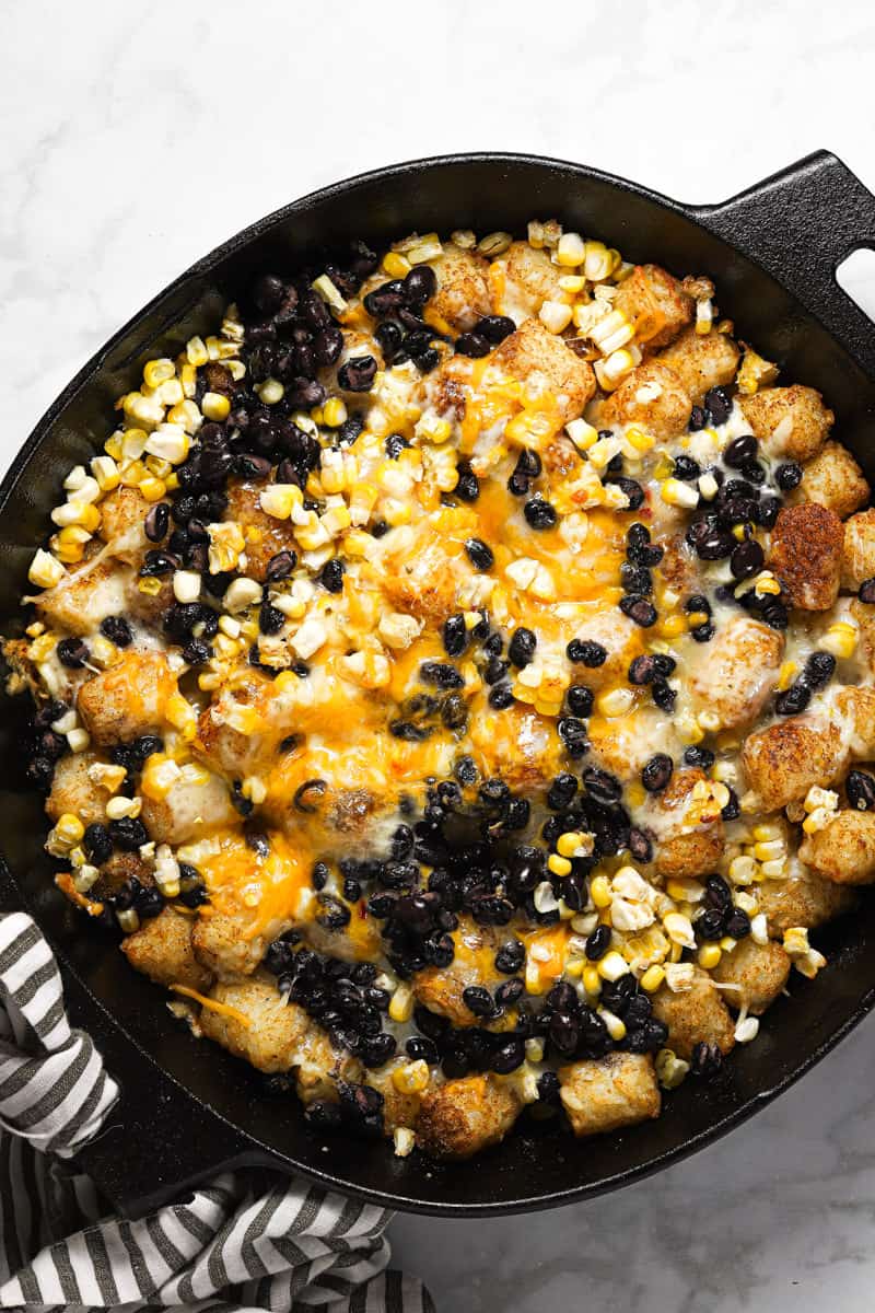 A cast iron skillet filled with freshly baked tater tot nachos