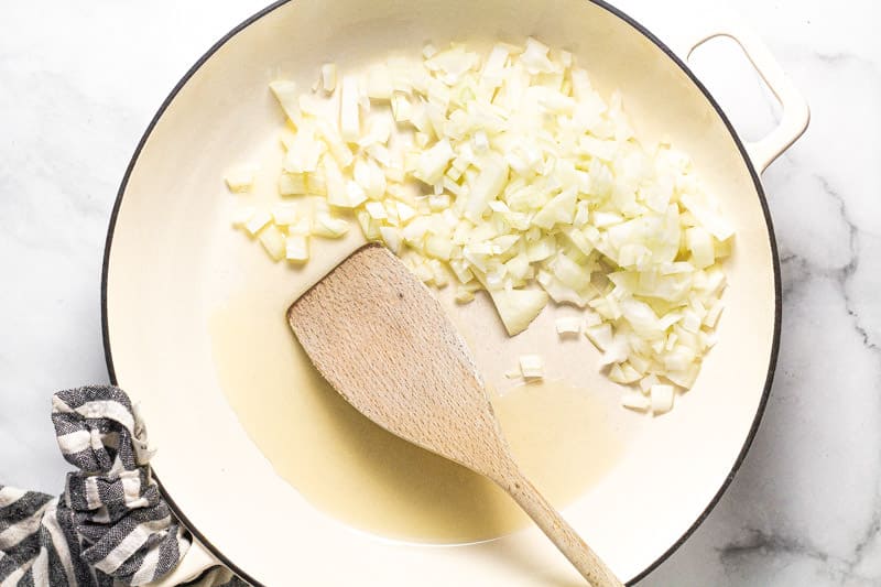 Large white pan with olive oil and diced onions 