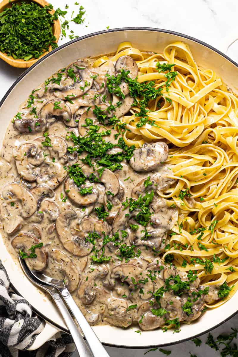 Large white pan filled with vegan mushroom stroganoff garnished with fresh chopped parsley 