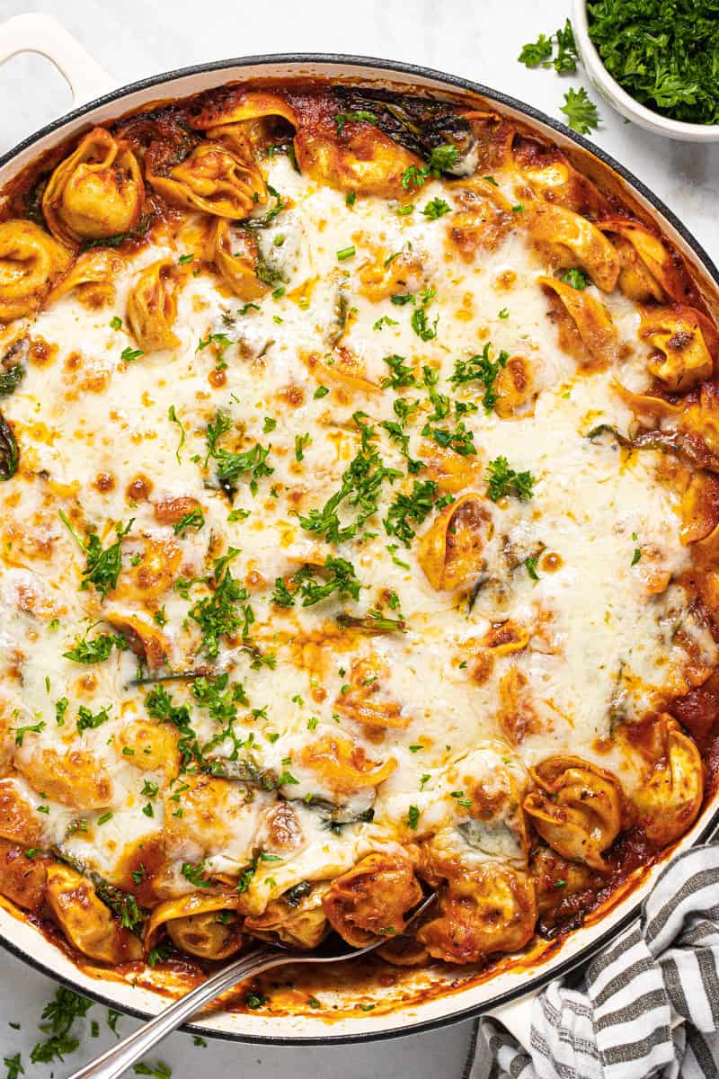 Large white pan filled with baked tortellini topped with melted cheese