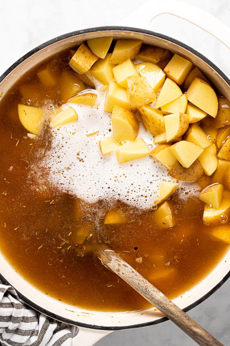 Large white pot with broth beer and diced potatoes for beer cheese soup