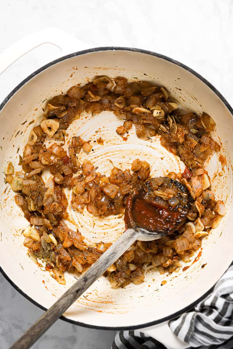 Large white pot with sautéed veggies and a bit of crushed tomatoes