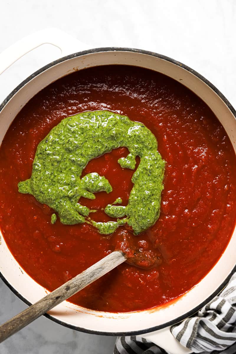 Large white pot with crushed tomatoes and basil pesto in it