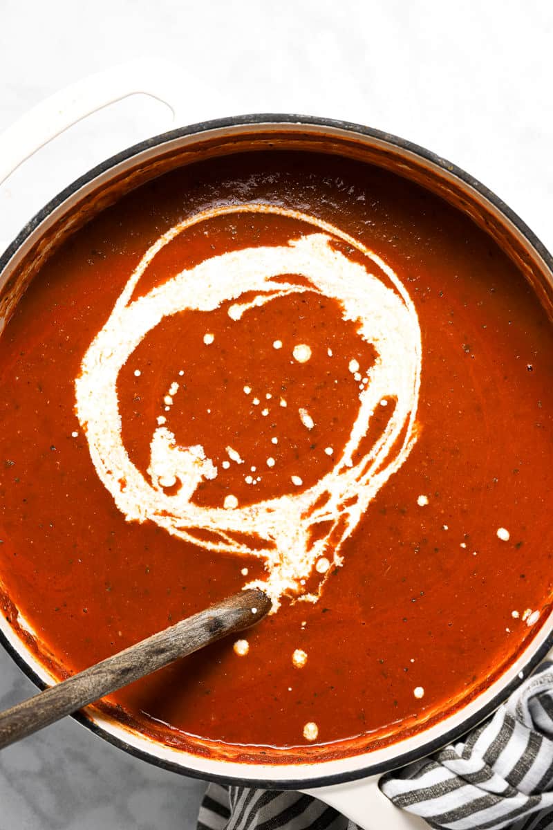 Large white pot a swirl of heavy cream added to tomato soup