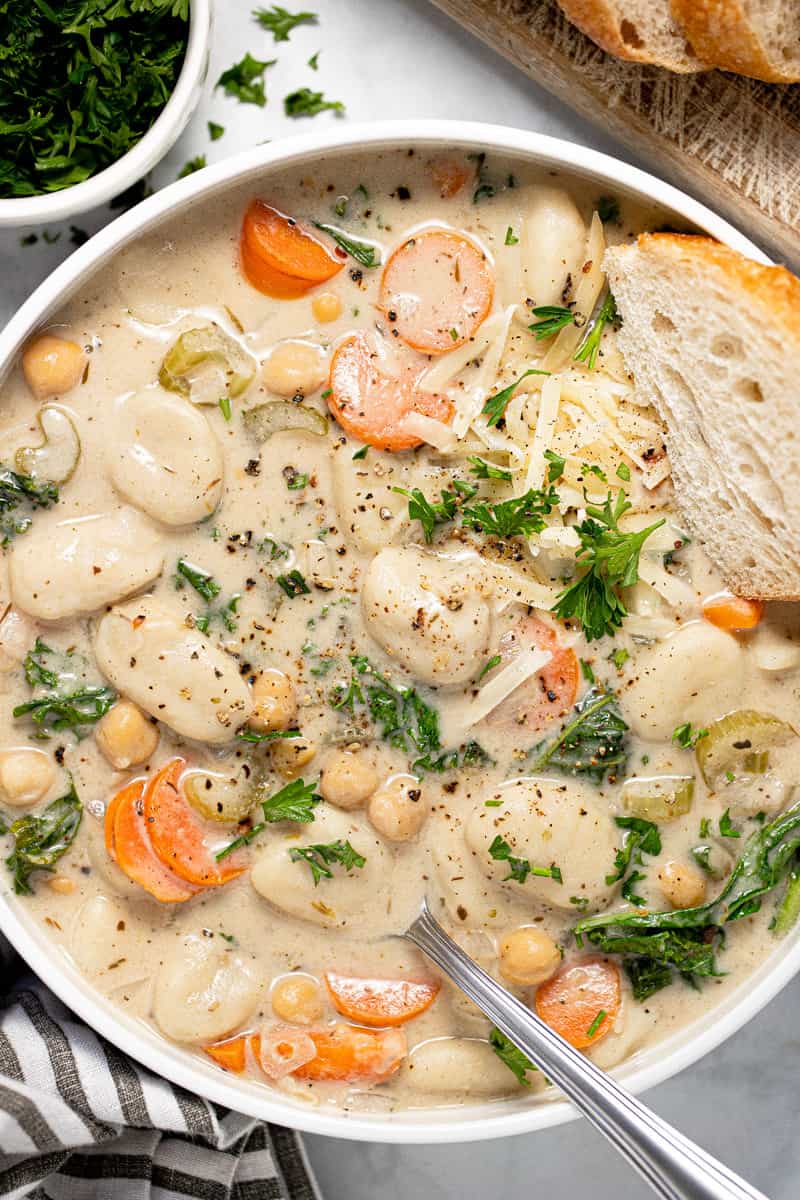 Large white bowl with creamy vegan gnocchi soup garnished with fresh chopped parsley 